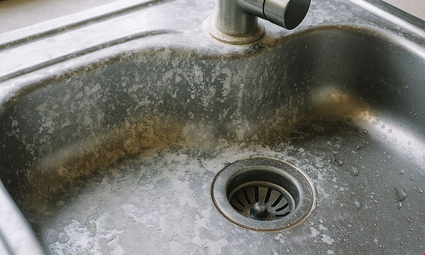 כיור נירוסטה עם הצטברות קשה של אבנית לבנה.