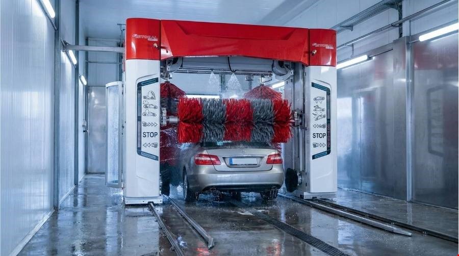 רכב במנהרת שטיפה אוטומטית עם מברשות בפעולה.